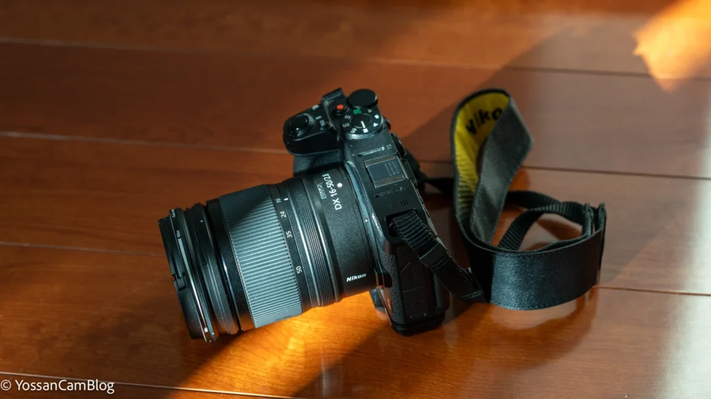 木目の床に置いたNikon Z30とNIKKOR Z DX 16-50mm f/2.8 VR。ストラップが伸びている
