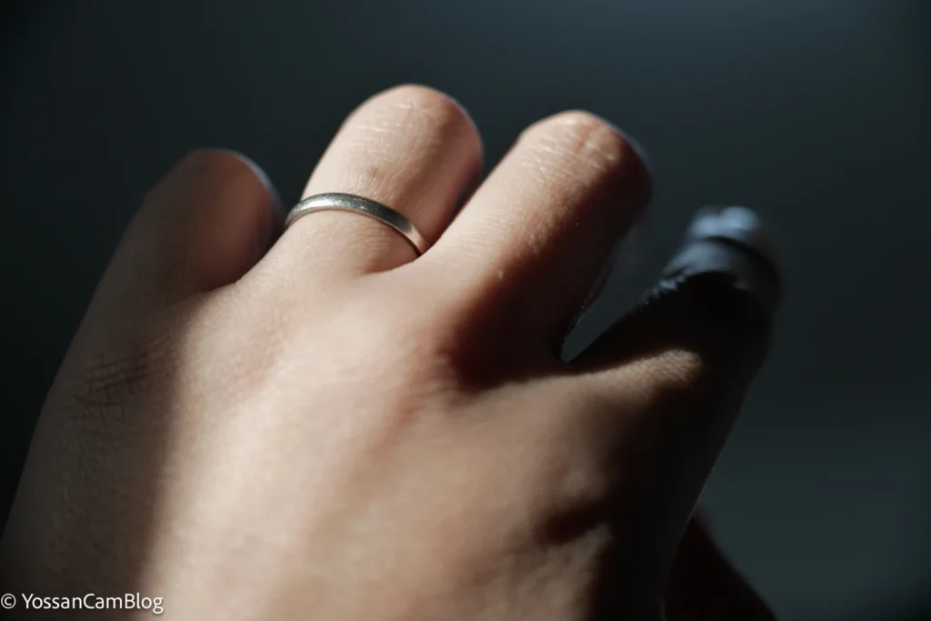窓からの光が当たった手の甲。結婚指輪が光り、背景は暗く落ちている