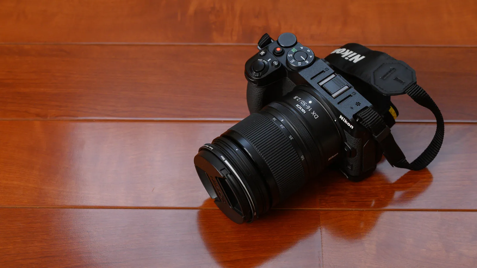 木目の床に置いたNikon Z30に、フィルターを付けたNIKKOR Z DX 16-50mm f/2.8 VRを付けたところ